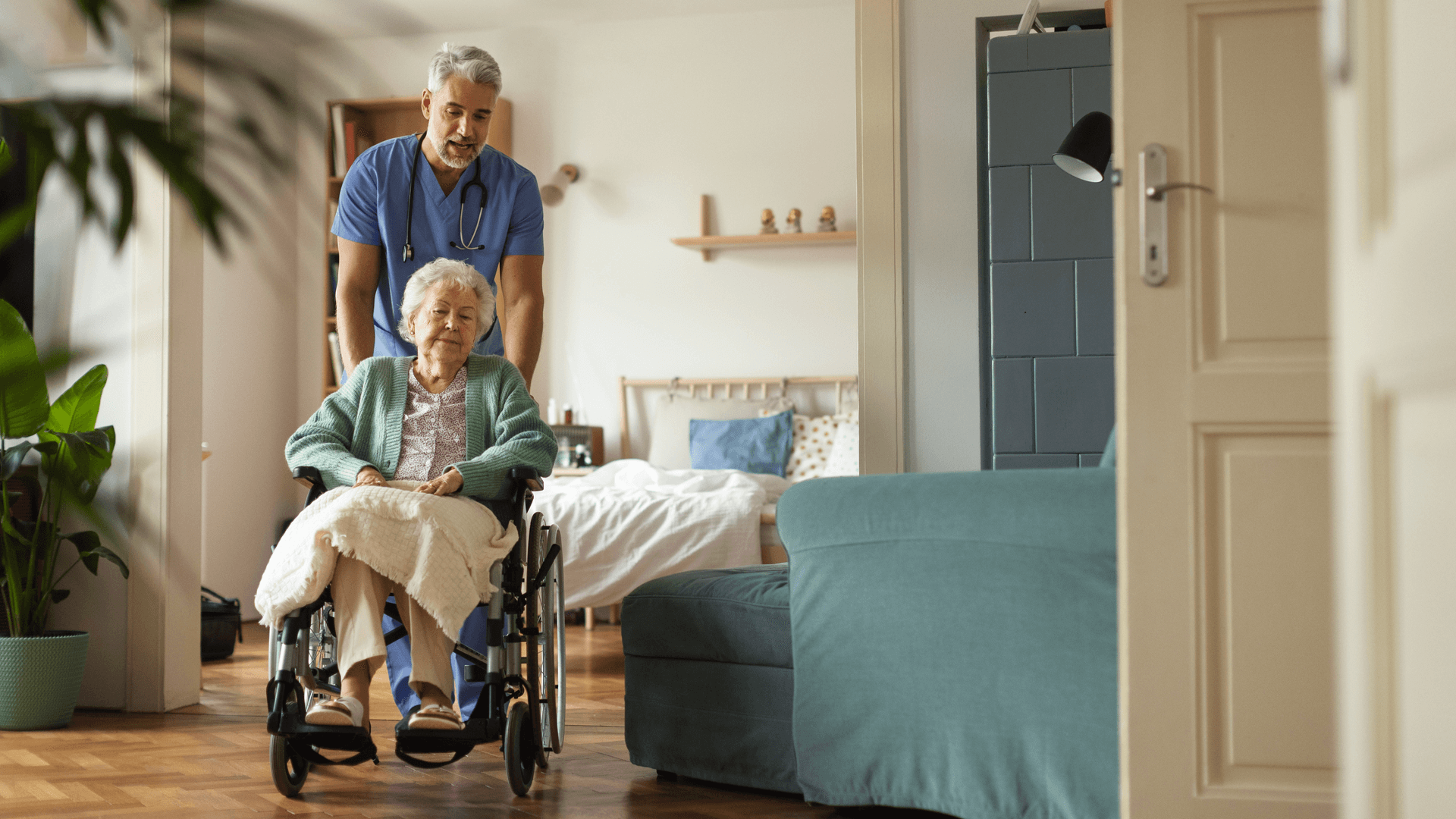 Male nurse pushing a patient in a wheelchair in a nursing home.