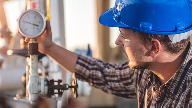 Worker checking the pressure next to a pipe