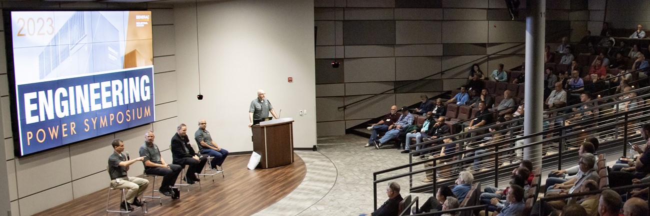 5 presenters on stage in a full auditorium at the Engineering Power Symposium