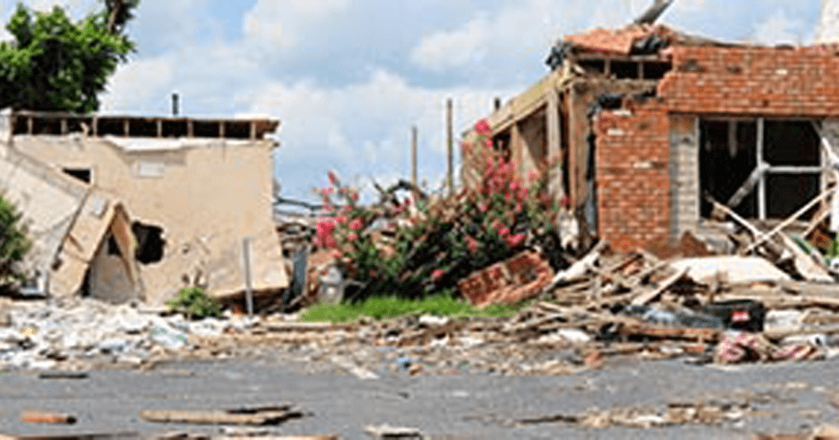 Two storefront buildings in wreckage after a weather disaster.