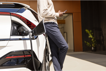 Person resting against a electric vehicle while it charges