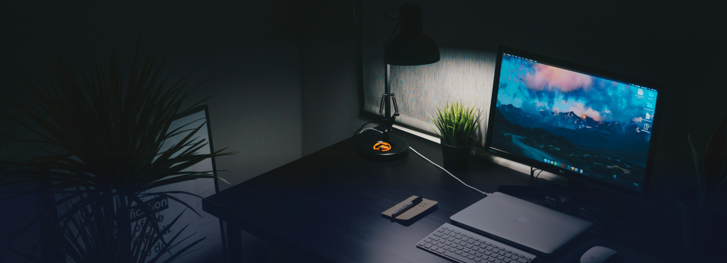 Laptop and lamp sitting on a desk in the dark