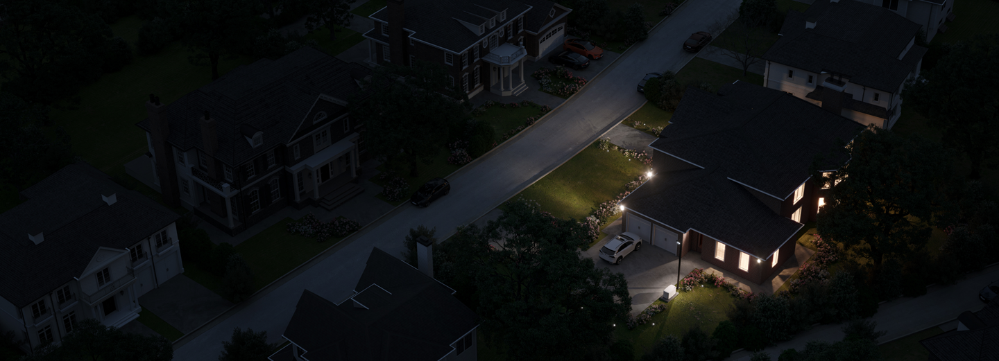 Aerial view of a dark street with one house with lights on