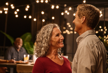 Happy people standing under string lights at night