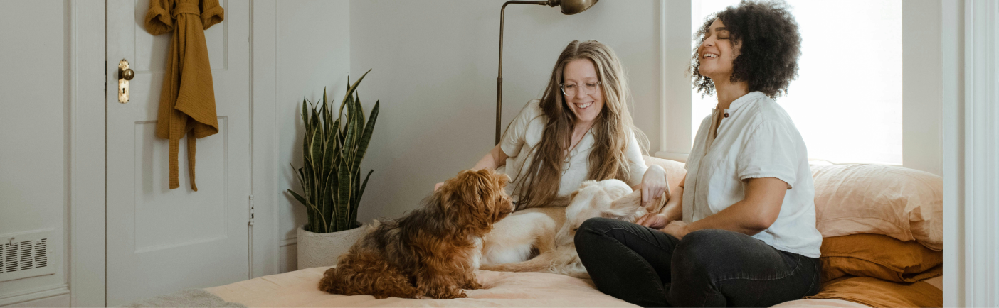 2 girls playing with a dog on a bed